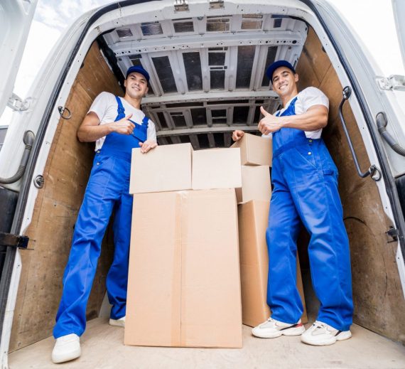 Deux ouvriers d'une entreprise de déménagement déchargeant des cartons d'un minibus.