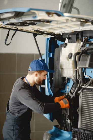 Le travailleur vérifie la qualité du camion dans le garage en uniforme